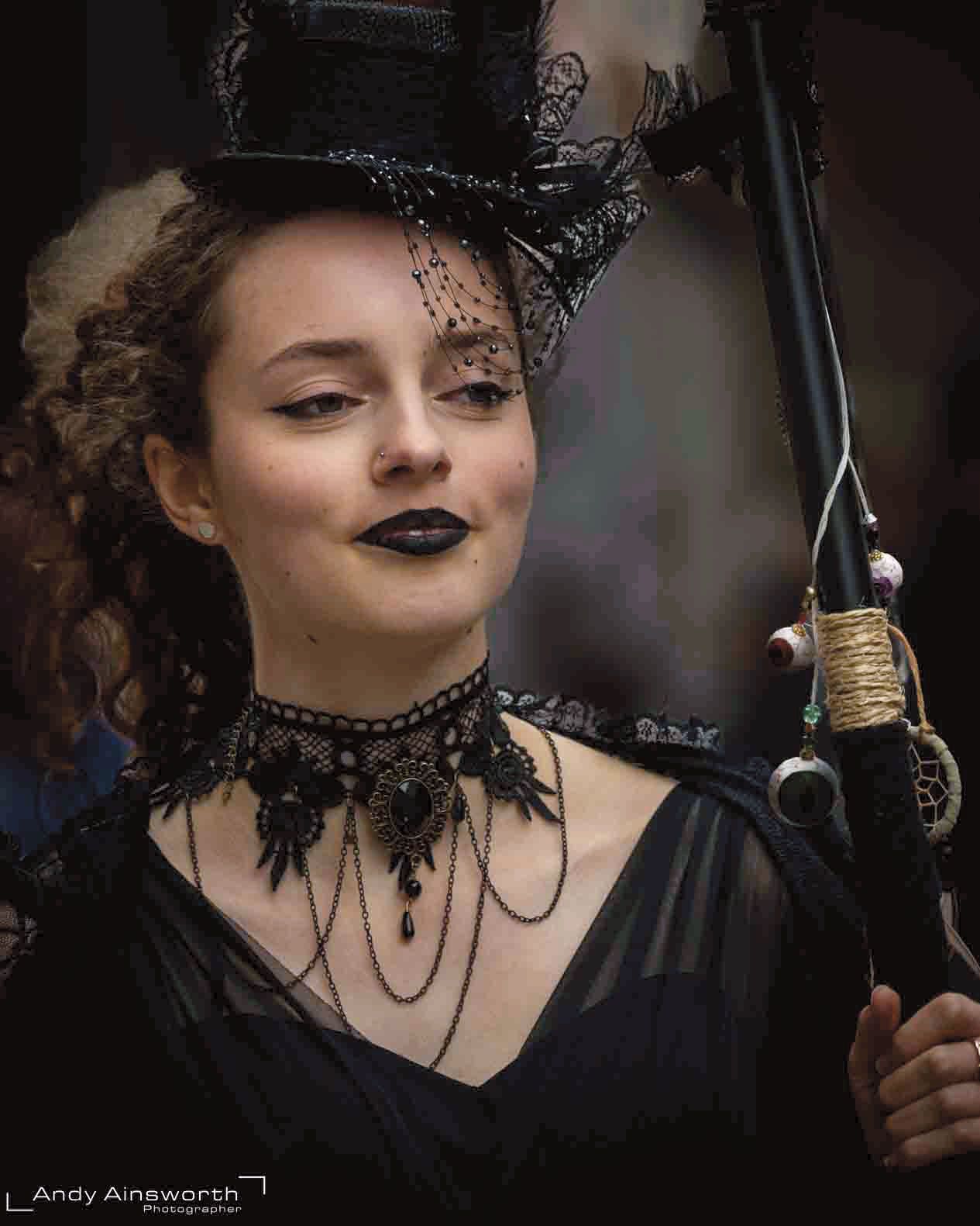 Woman in a black top hat and lace choker, dark lipstick, glancing aside — Whitby Goth Weekend