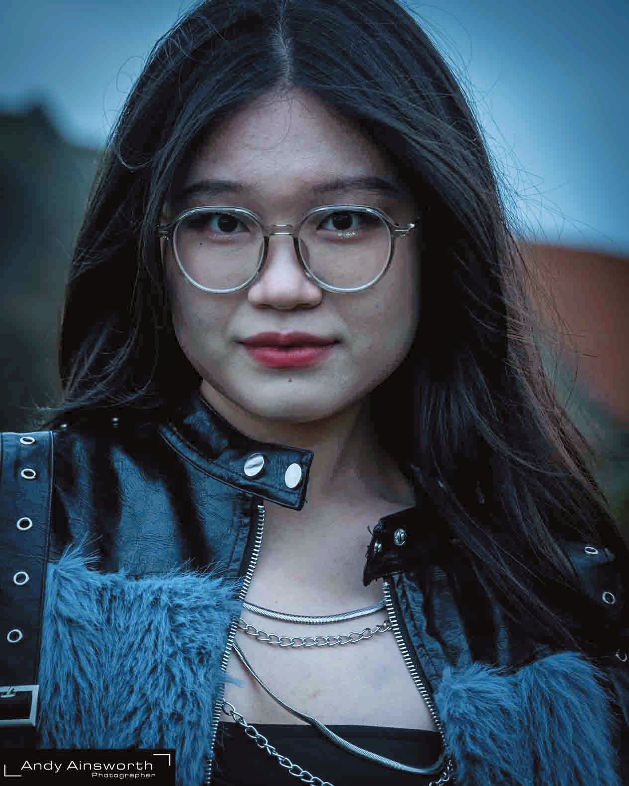 Young woman in round glasses and a blue fur-collared jacket with chains — Whitby Goth Weekend