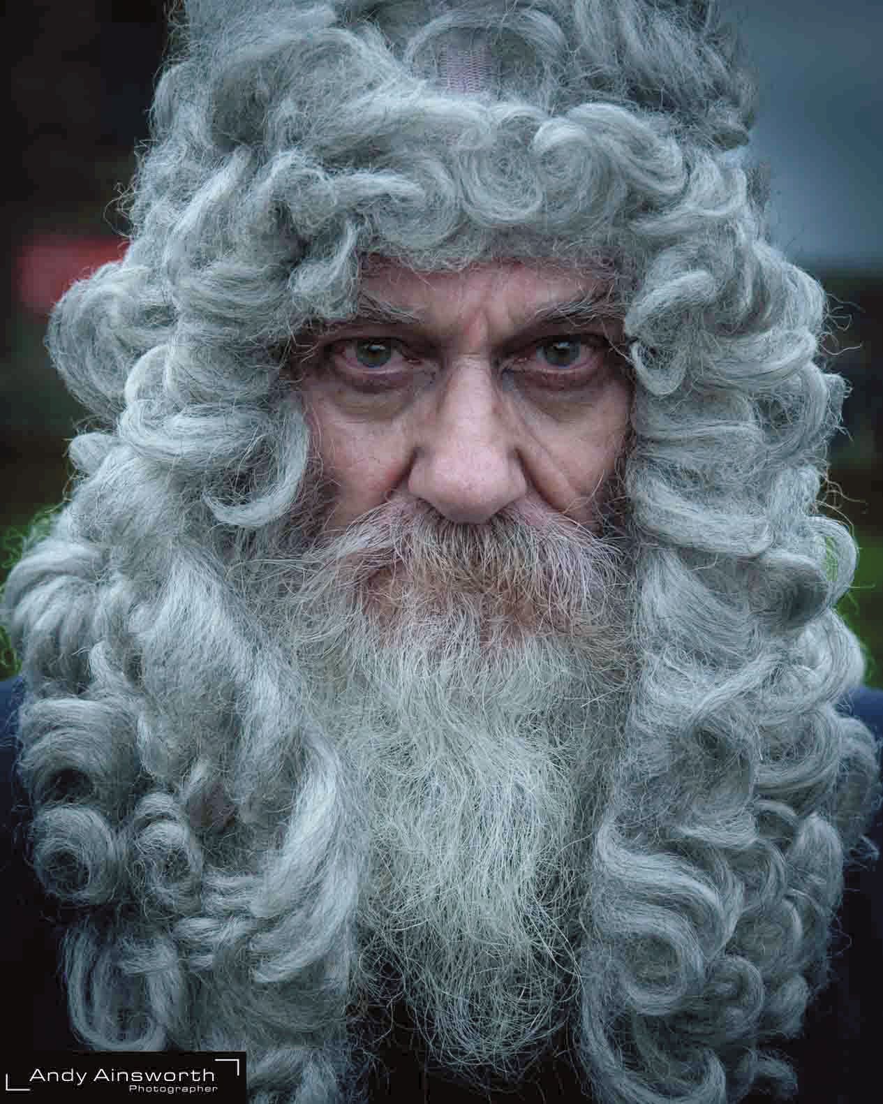 Man in an enormous curly silver wig with a grey beard, eyes to the lens — Whitby Goth Weekend