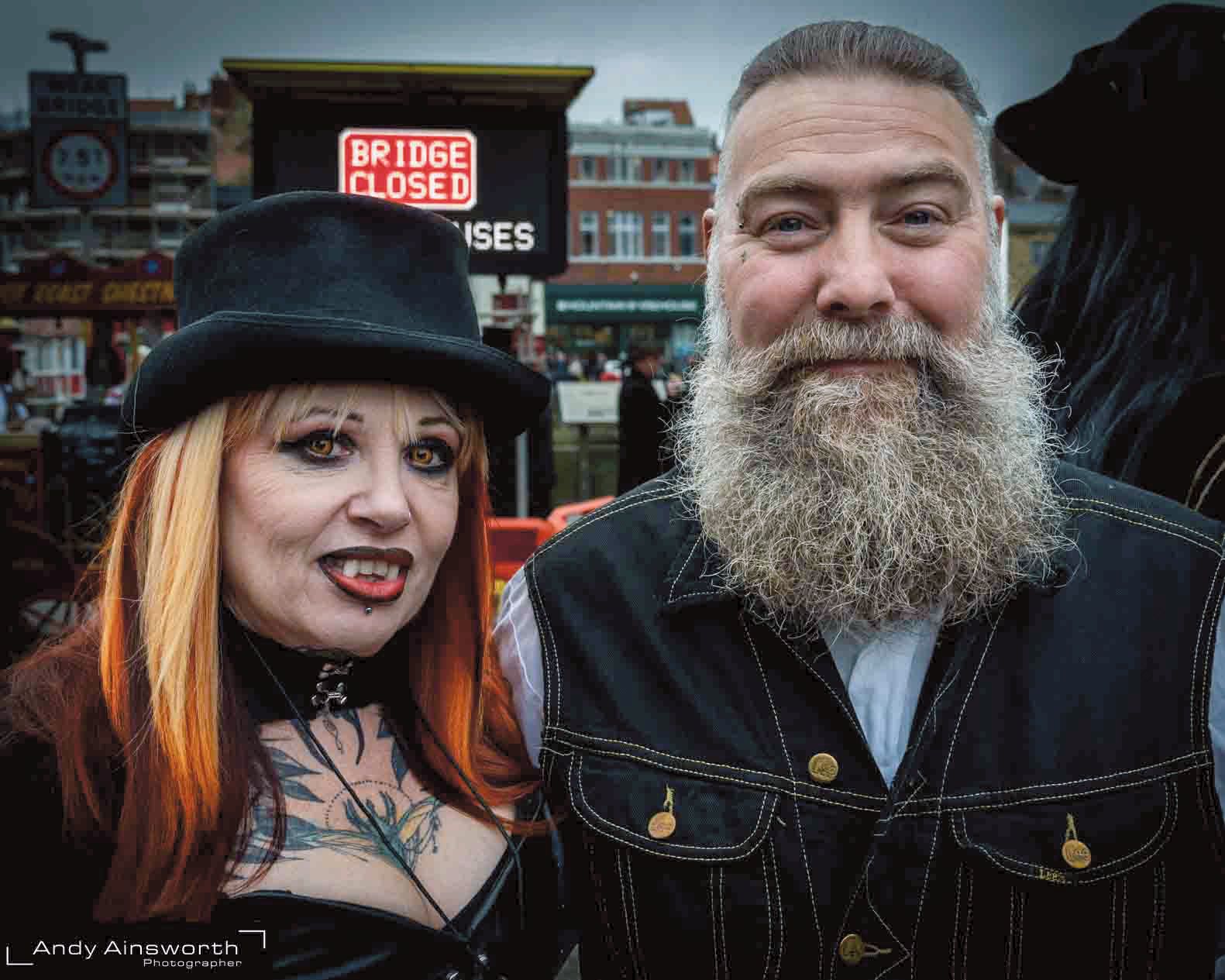 Couple in the street — red-haired woman in a top hat and a bearded man in a waistcoat — Whitby Goth Weekend