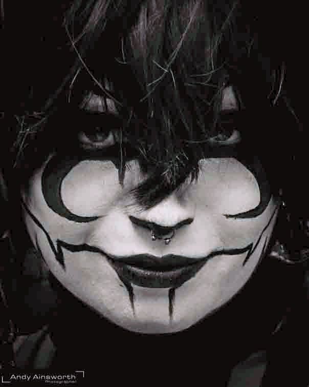 Painted white face with a dark curved smile glimpsed through black hair, black and white — Whitby Goth Weekend