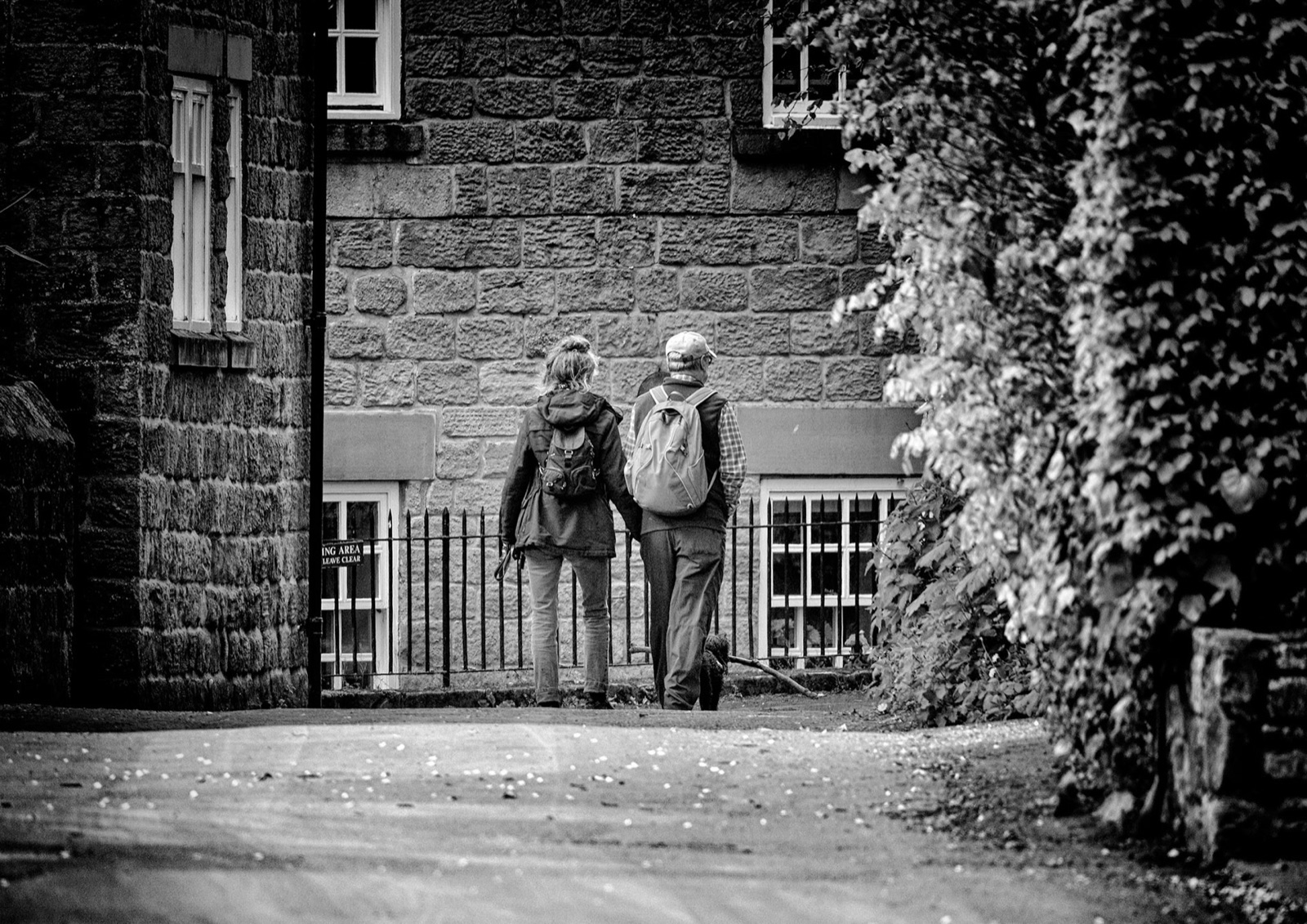 Two walkers chatting beside an ivy-covered stone barn — Knaresborough photowalk