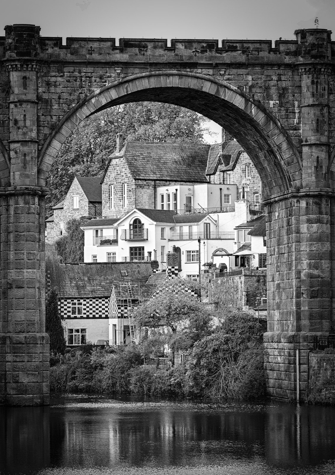 Church and hillside houses framed through a viaduct arch — Knaresborough
