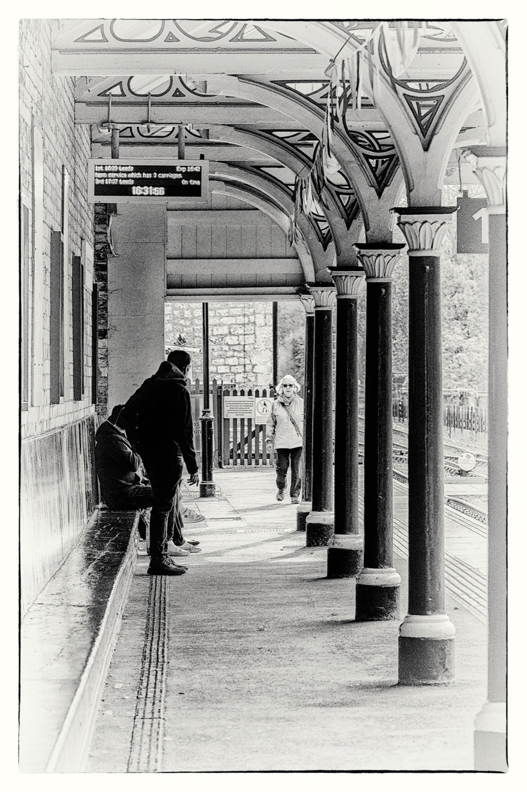 Passenger waiting beneath the station colonnade — Knaresborough platform study