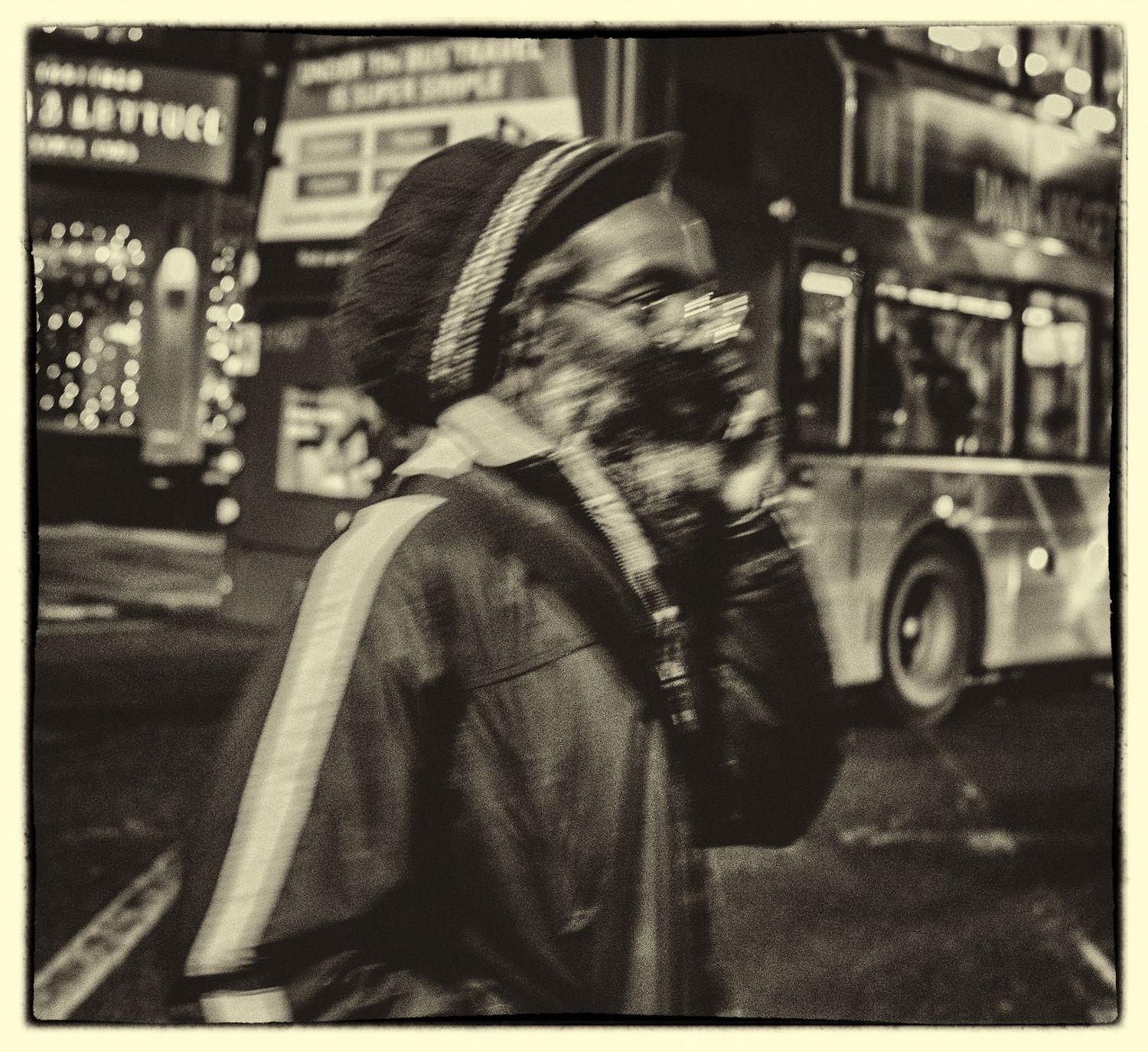 Woman in a headscarf glancing back as a lit bus passes — Leeds night street photography